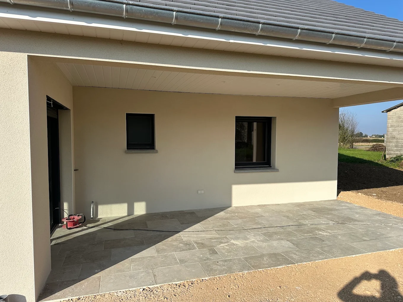 Enduit clair autour des fenêtres et de la porte sous une terrasse couverte
