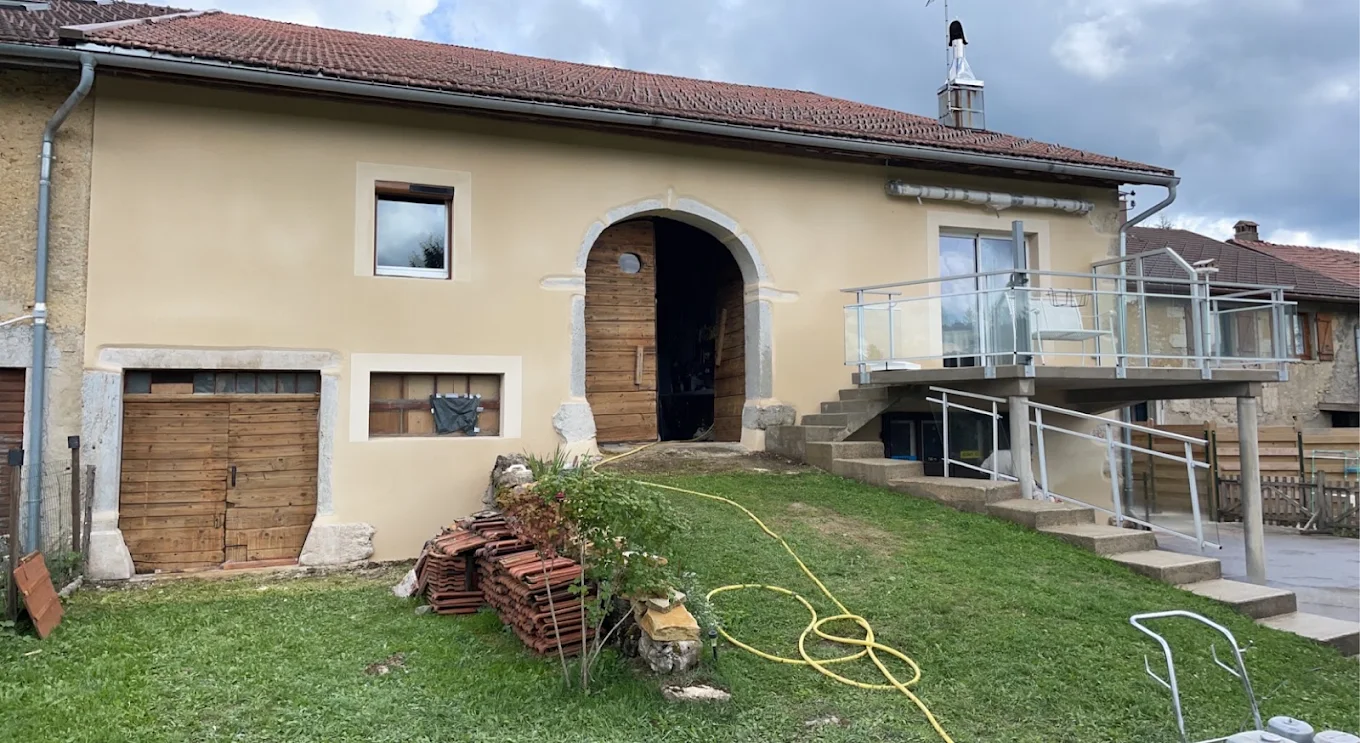 Maison ancienne avec enduit beige et encadrements de porte et fenêtres en pierre